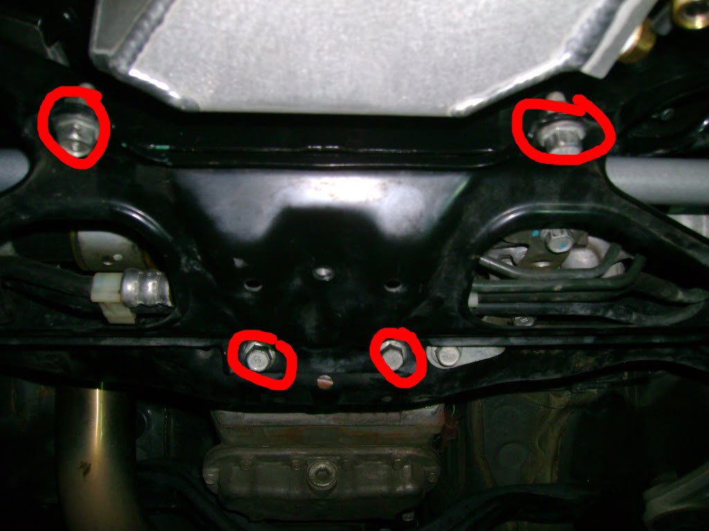 Subaru STi: Remove the subframe lower brace as seen here. Ten total bolts, all 14mm (two have 14mm nuts) and you may need your impact/breaker bar. There are four center bolts as circled below (note that the forward two have a nut instead of threads into the subframe).